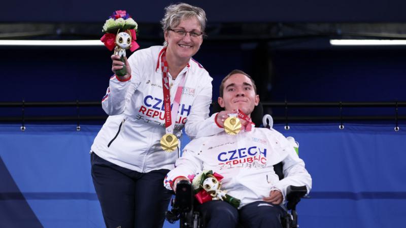 Adam Peska and Ivana Peskova smiling with their gold medals 