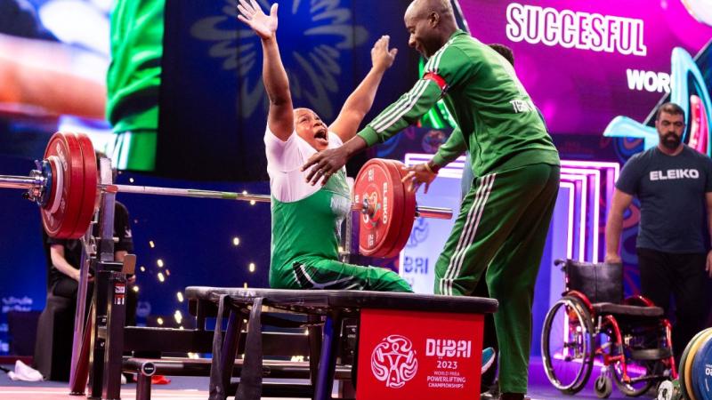 A female powerlifter celebrating with her male coach