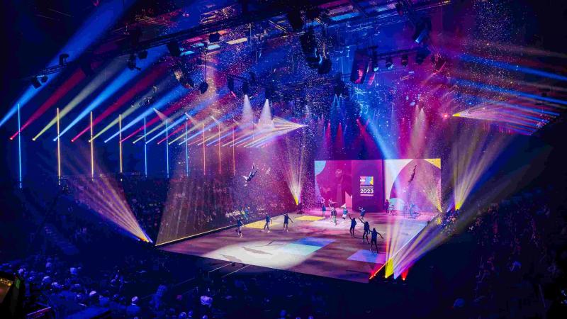 dancers performing on a stage surrounded by brightly coloured light beams