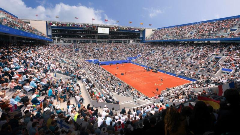 a wide shot of a clay tennis court surrounded by spectators 