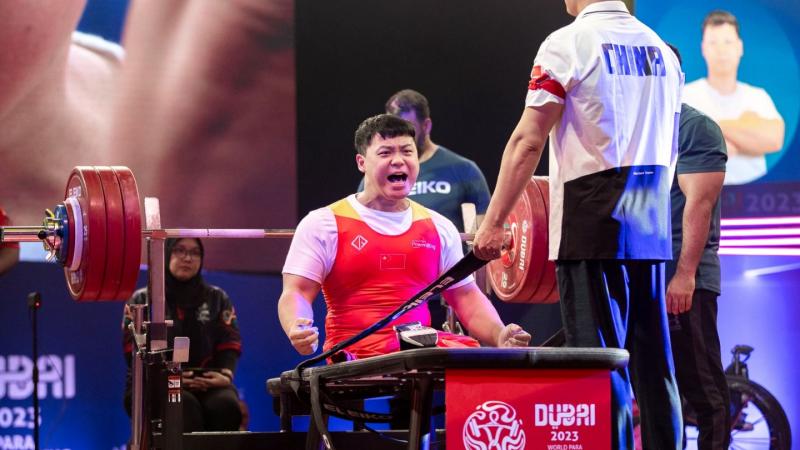 A male athlete celebrating on a bench press during a Para powerlifting event