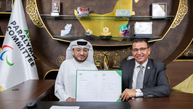 Two men sit next to each other holding a contract