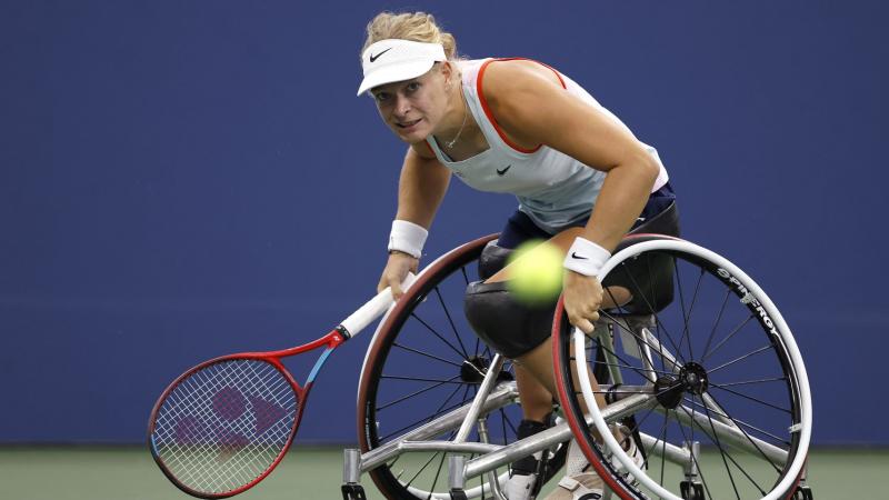 A female wheelchair tennis player hits a ball during ca game.
