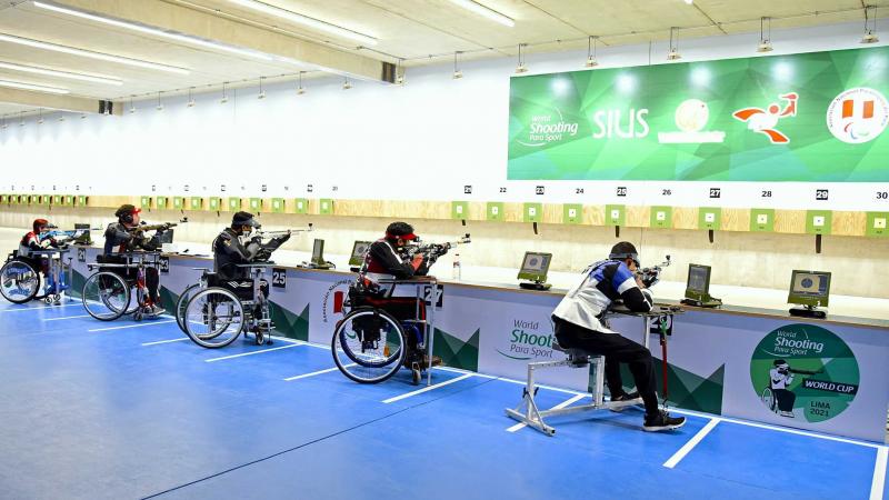 Five shooters competing in a rifle event in a shooting range