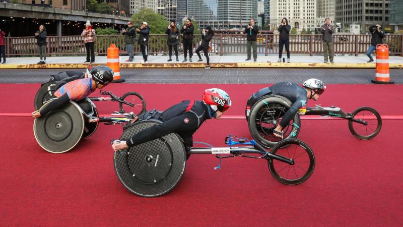 Three male wheelchair racers in a street marathon