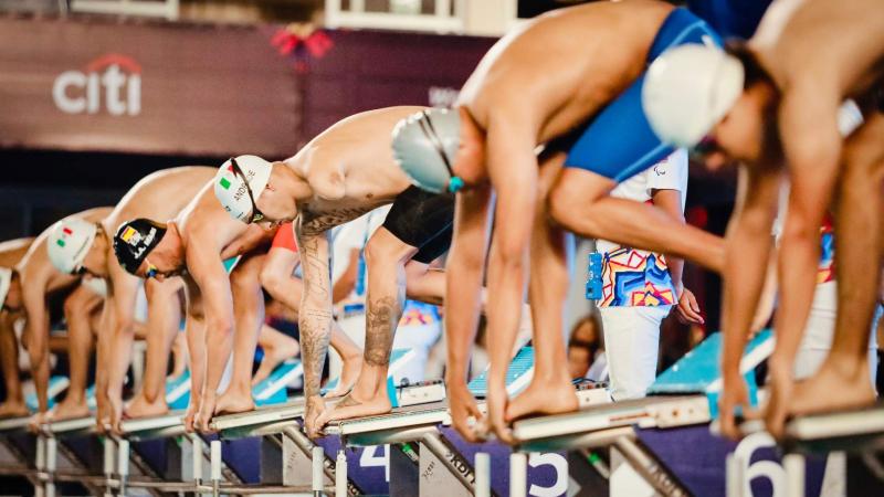 Six men on starting blocks of a Para swimming race