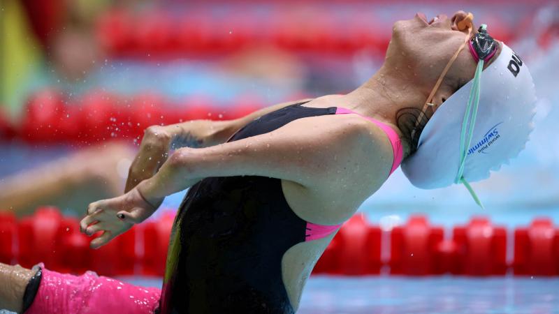 A female swimmer jumping in the water in a backstroke race