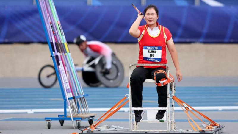 A female seated javelin thrower in a Para athletics competition