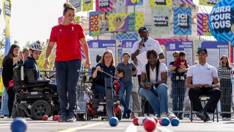 People demonstrate playing boccia in front of a crowd