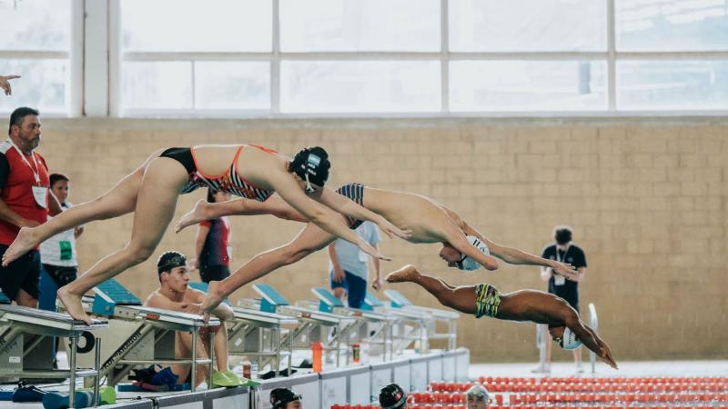 Three Para swimmers jump into the pool