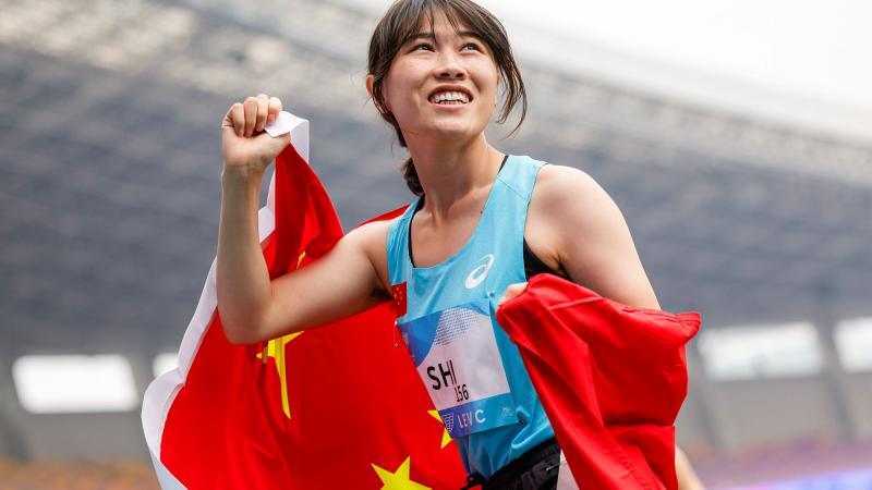 A female athlete with a Chinese flag in a athletics stadium