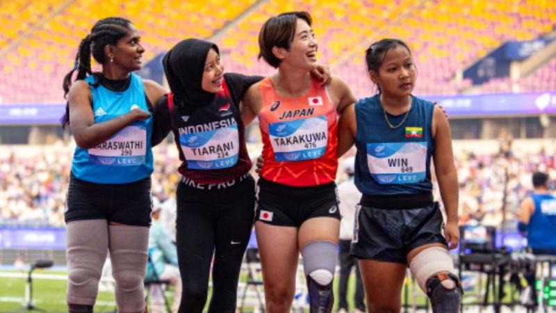 Four female athletes with running blades look to their left side