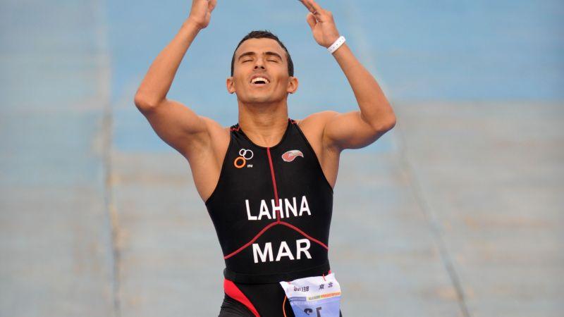 A picture of a man with a prosthesis crossing a finish line and celebrating his victory