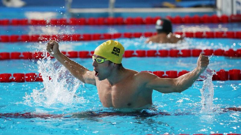 A male swimmer with a cap of Brazil celebrating in the pool