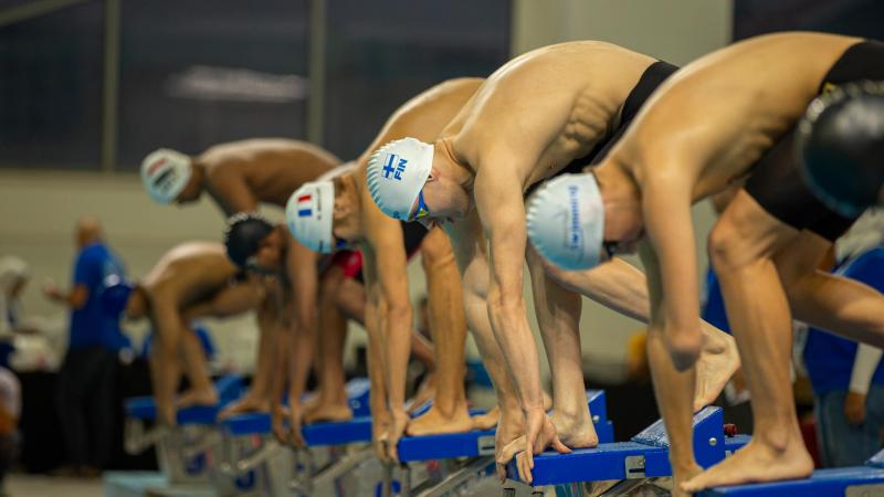 Seven Para swimmers on the starting block before a race