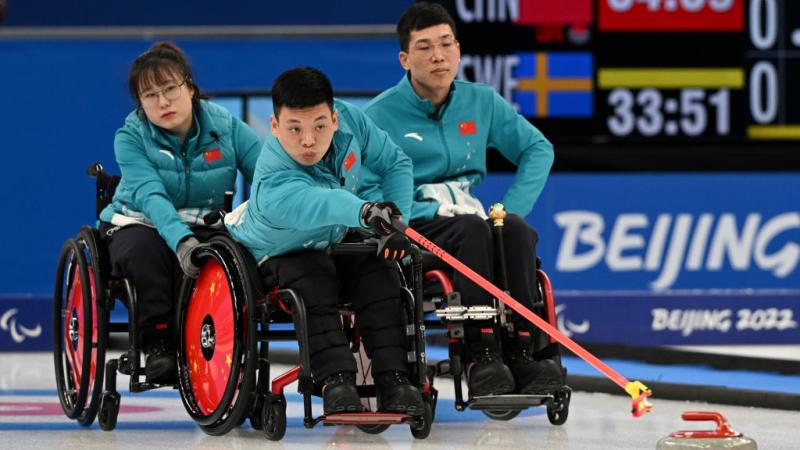 Three wheelchair curling athletes on the ice at Beijing 2022