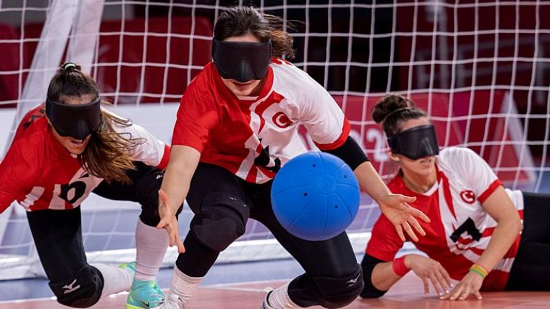 Three female players wearing eyeshades compete in goalball