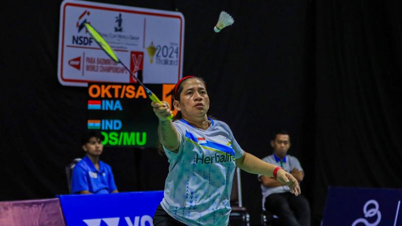 A female Para badminton player reaches for the shuttle during a Para badminton match