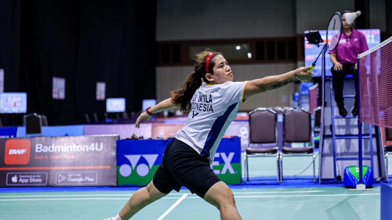 A female Para badminton player reaches for the shuttle during a Para badminton match