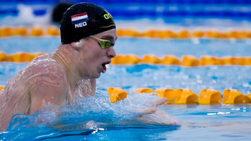 A male swimmer with a cap with the Dutch flag