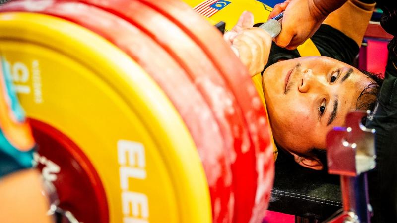 A man on a bench press looking at the discs