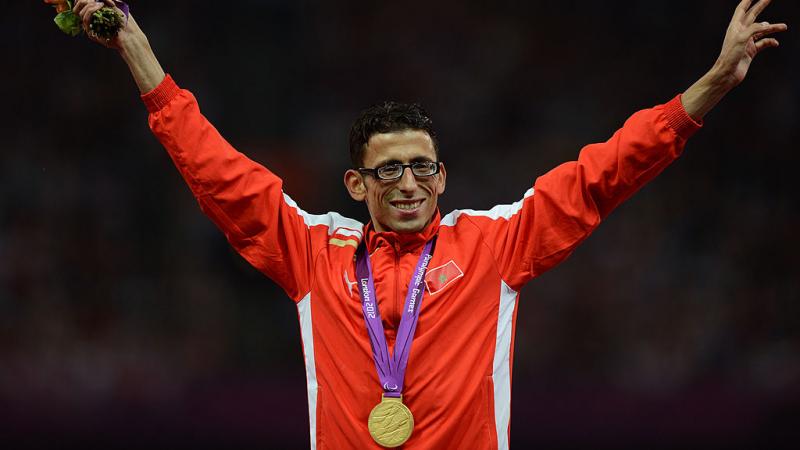Para athlete El Amin Chentouf holds his arms out to celebrate with a gold medal around his neck
