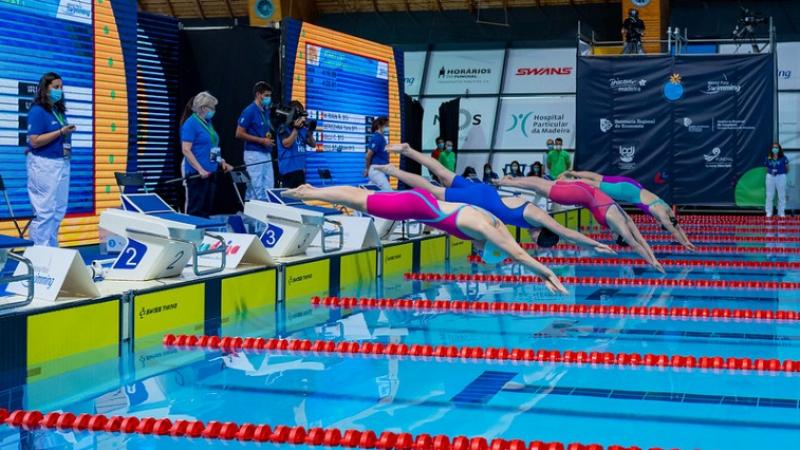 Four female Para swimmers jump in the water