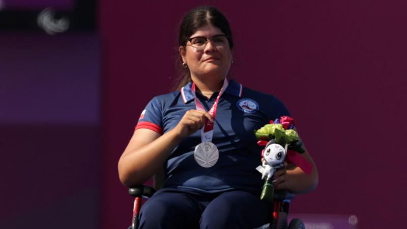 Para archer Mariana Zuniga holding up her silver medal on the podium 