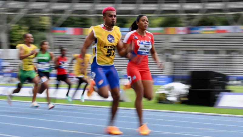 A female sprinter and her male guide race. They are in front of a pack of athletes.
