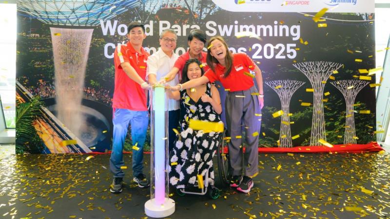 A woman in a wheelchair and four persons standing pressing a button