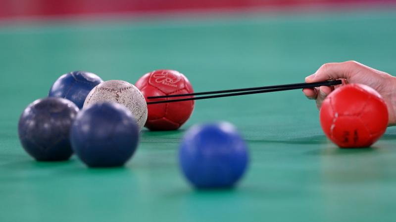 a group of blue and red balls lying close to a white ball being measured 