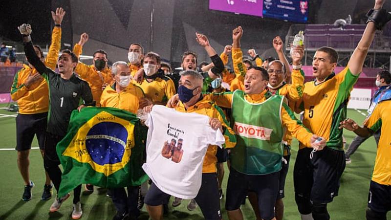 a group of Brazilian blind footballers holding up flags and cheering