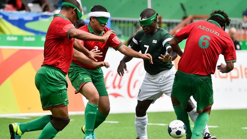 A group of Moroccan blind footballers surround a Brazilian player with the ball 