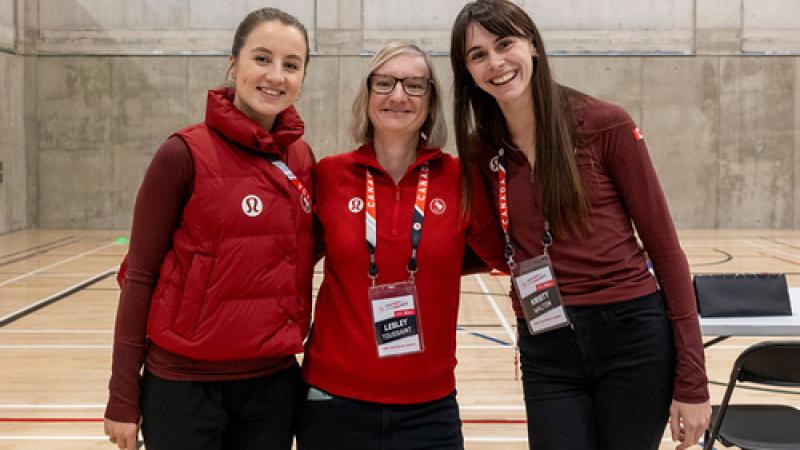 Three women wearing Canada's red uniforms pose for a photo
