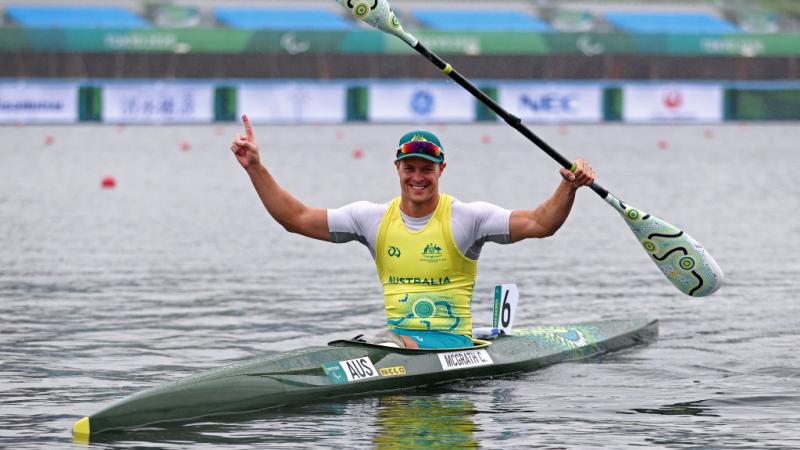 Male Para canoeist Curtis McGrath raises his arms in celebration