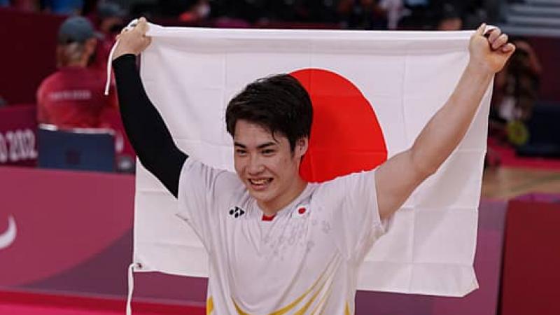 Para badminton player Daiki Kajiwara holds up the Japan flag in celebration