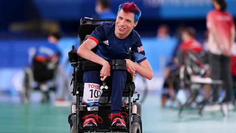 Boccia player David Smith smiles at the camera from a powered wheelchair 