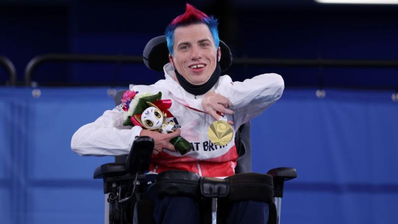 Boccia player David Smith holds up his gold medal and smiles
