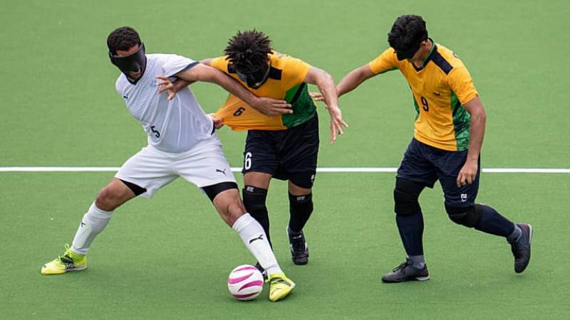 three blind footballers fight for the ball 