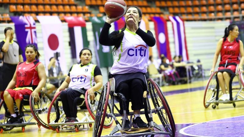 A female wheelchair basketball player is about to throw the ball during a match.