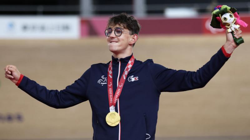 Para cyclist Alexandre Leaute holds his arms up in celebration on the podium