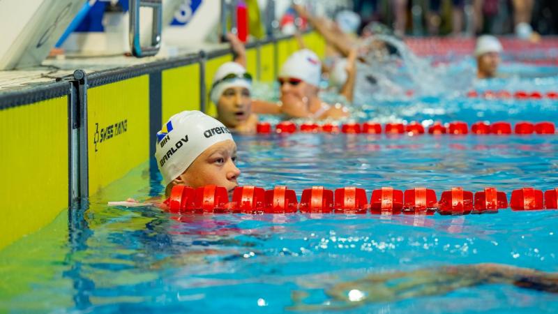 A male swimmer in a swimming pool lane with other swimmers in the background