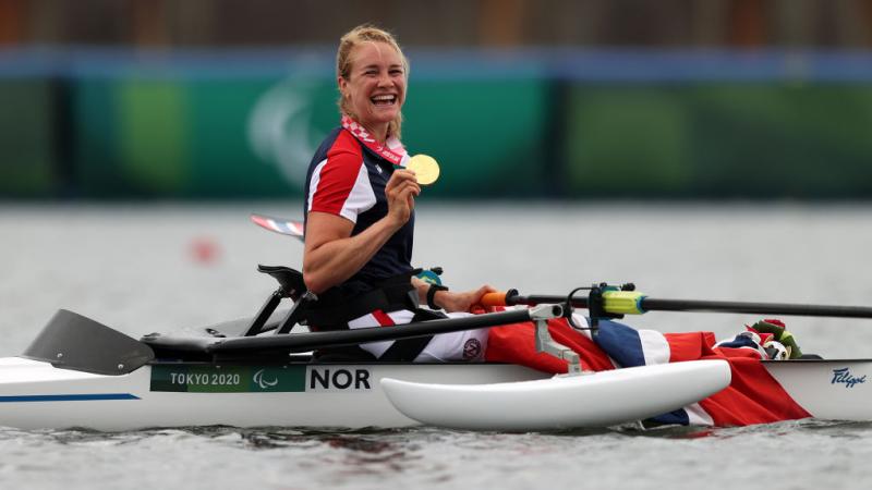 Para rower Birgit Skarstein in her boat holding her gold medal and smiling 