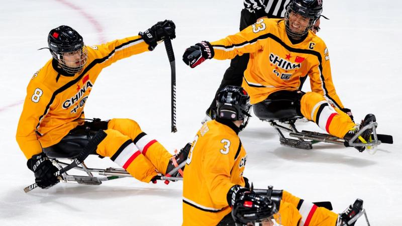 Three Chinese Para ice hockey players celebrating in a game