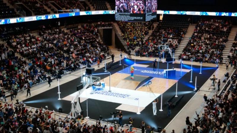 A wide shot of a basketball court. Many people are in the stands