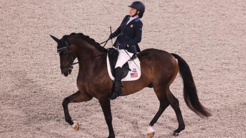 Female Para rider Rebecca Hart using the reins to direct her horse