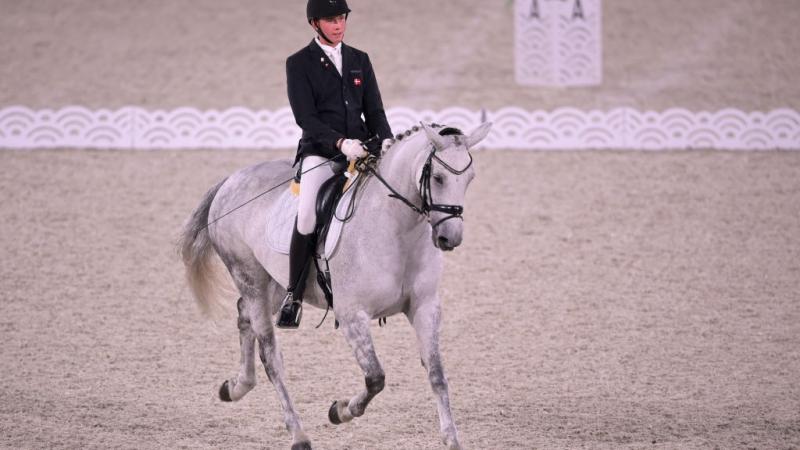 Tobias Jorgensen, a Para equestrian athlete from Denmark, rides a white horse at the Tokyo 2020 Paralympics.