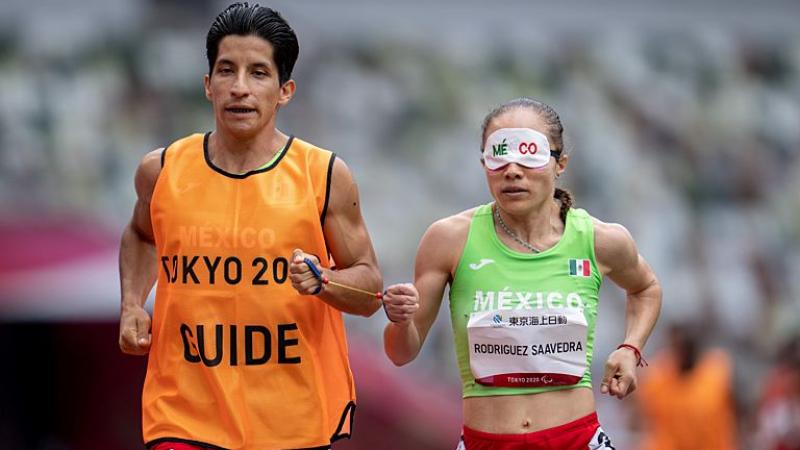 A Para athlete runs with his guide  