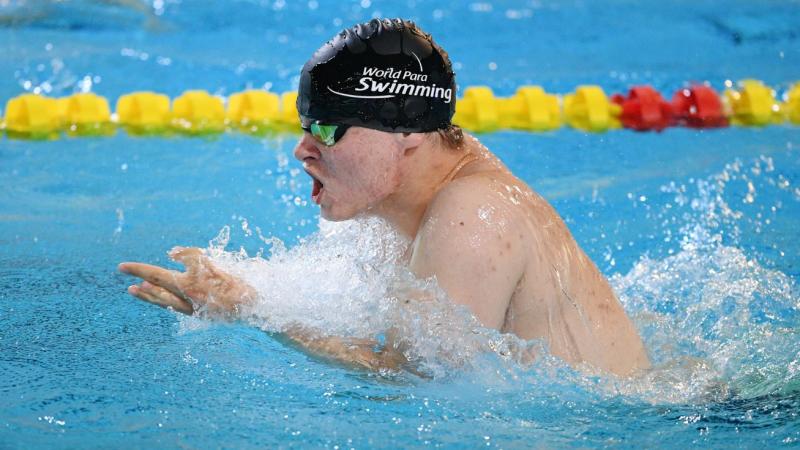A man with black cap swimming breaststroke 