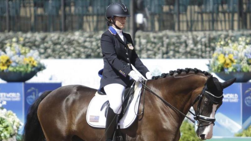 A female Para equestrian athlete rides a horse